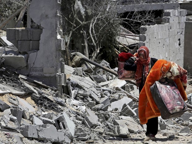Mulher retira pertences dos destroços na Faixa de Gaza (Foto: G1)